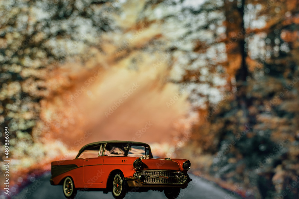 Retro car toy model in front of the autumn forest background