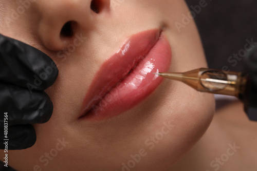 Young woman undergoing procedure of permanent lip makeup in tattoo salon, top view