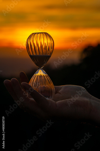 the planet is in danger .. time is running out .. how many more sunsets are there? hourglass on sunset background