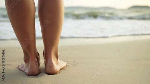 The woman feet relaxed are lying on the sandy beach and washed b