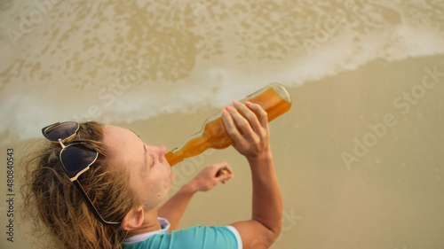 View top woman in swimwear on the beach drinks alcohol. Parting photo