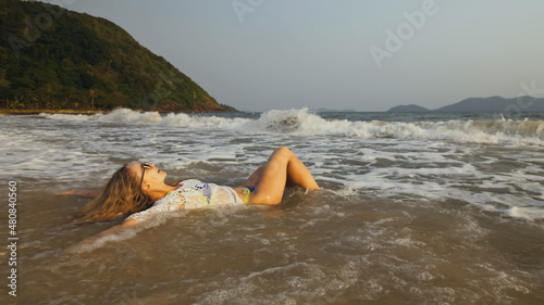 Woman in a White Tunic on the Beach, near the Sea. Blonde in Sunglasses. Tourist Enjoying Vacation Time, Running on Water, Walks has Fun.