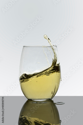 Glass cup with drink in motion with a white background