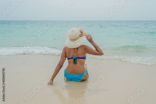 Espalda de mujer en traje de baño posando sentada en Playa Blanca Barú en Cartagena en Colombia © Josuhe
