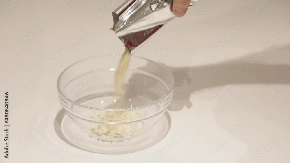 Men Pouring Oatmeal From Mylar Bag in Glass Bowl Men Pouring Oatmeal From Mylar Bag in Glass Bowl