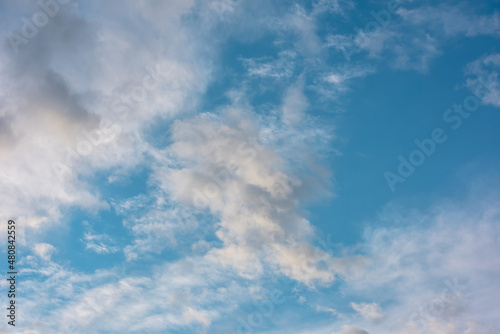 Scenic view to clouds illuminated by sunset in blue sky. Nature background of cloudy sky in sunrise. Beautiful landscape with sunset lit clouds in evening sky. Nature texture of sunset cloudy skies.