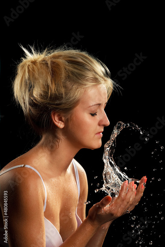 Portrait of beautiful young woman with drops of water around her face. Close-up portrait on dark background