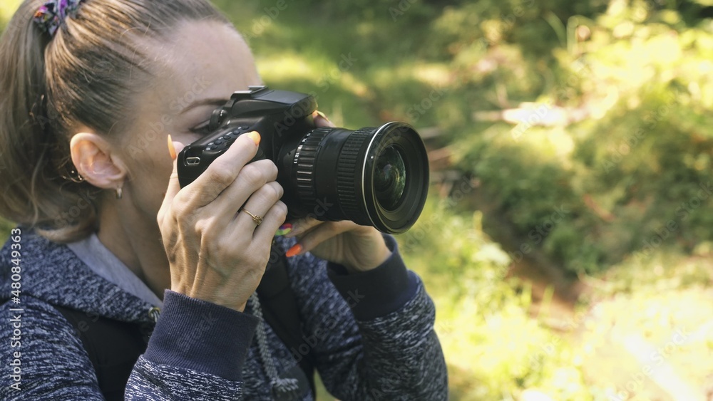 Traveler photographing scenic view in forest. One caucasian woman shooting close up look. Girl take photo video on dslr mirrorless camera. Traveler photographing scenic view in forest. One caucasian woman shooting close up look. Girl take photo video on dslr mirrorless camera.