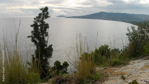 View from the roof top of an old medieval fort of the U shaped beasch of the island and the vast blue sea on a cloudy day. photo