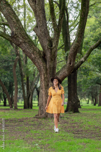 Young Mexican woman walking through the forest with a big tree in the background