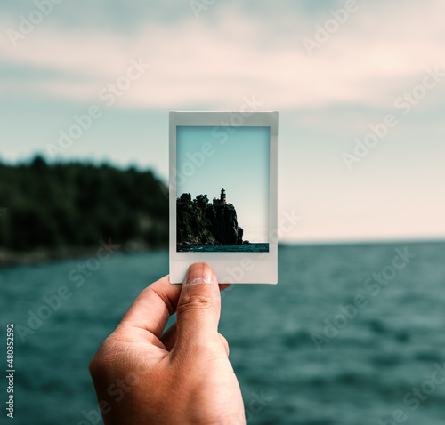 Картината върху платно HOLDING POLAROID OF LIGHTHOUSE ON LAKESIDE
