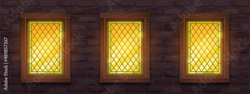 Old brick wall with glow stained glass windows at night. Vector cartoon illustration of medieval building facade with mosaic windows in wooden frame and stone wall