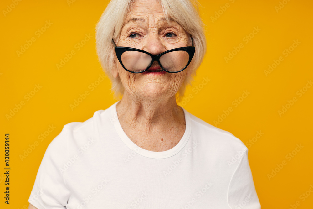 smiling elderly woman in a white t-shirt wears glasses isolated background smiling elderly woman in a white t-shirt wears glasses isolated background