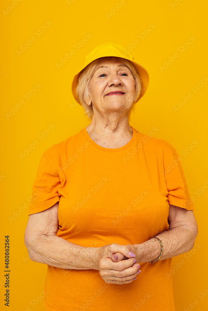 Photo of retired old lady in yellow t-shirts hat posing cropped view Photo of retired old lady in yellow t-shirts hat posing cropped view