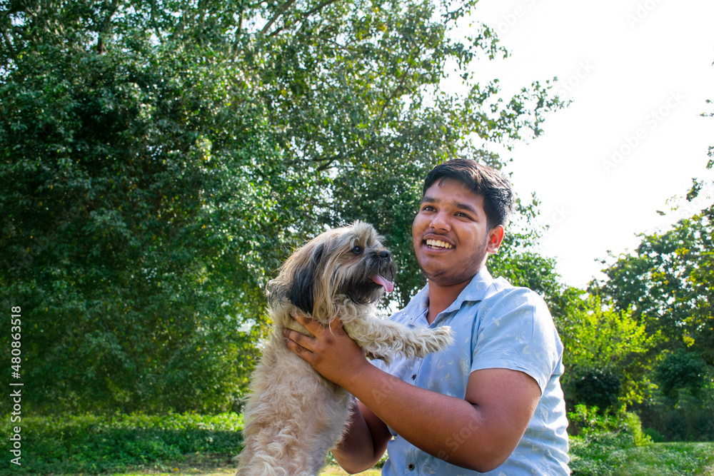 young man playing with dog at park