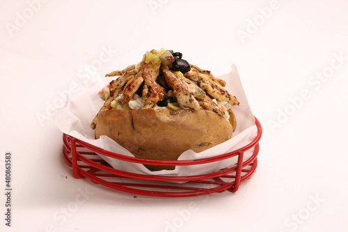 Baked kumpir potato stuffed with the cheese, sausage, olives, peppers and corn photo