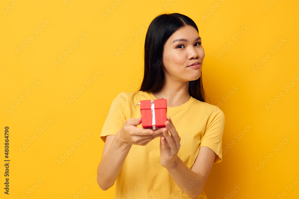 woman with Asian appearance in a yellow t-shirt holiday gift emotions Lifestyle unaltered woman with Asian appearance in a yellow t-shirt holiday gift emotions Lifestyle unaltered