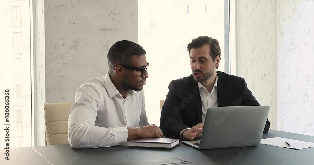 African and Caucasian businessmen accomplish meeting shake hands. Multi racial colleagues teammates sit at desk speaking over collaborative corporate task, finish working handshaking. Teamwork concept African and Caucasian businessmen accomplish meeting shake hands. Multi racial colleagues teammates sit at desk speaking over collaborative corporate task, finish working handshaking. Teamwork concept
