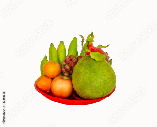 Fototapeta Naklejka Na Ścianę i Meble -  mixed fruit on red plastic bowl  such as : pomelo,dragon fruit, orange,banana on a white background . natural food concept, fruit for chinese new year  ,