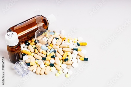 Brown bottles and many colorful medicines and pills. Brown glass medical bottles for potions and various medicines. Composition on a light background. Copy space