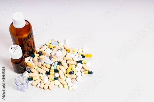 Brown bottles and many colorful medicines and pills. Brown glass medical bottles for potions and various medicines. Composition on a light background. Copy space
