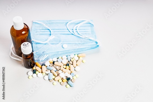 Brown bottles, a lot of colorful medicines and pills, a medical mask. Brown glass medical bottles for potions and various medicines. Composition on a light background. Copy space