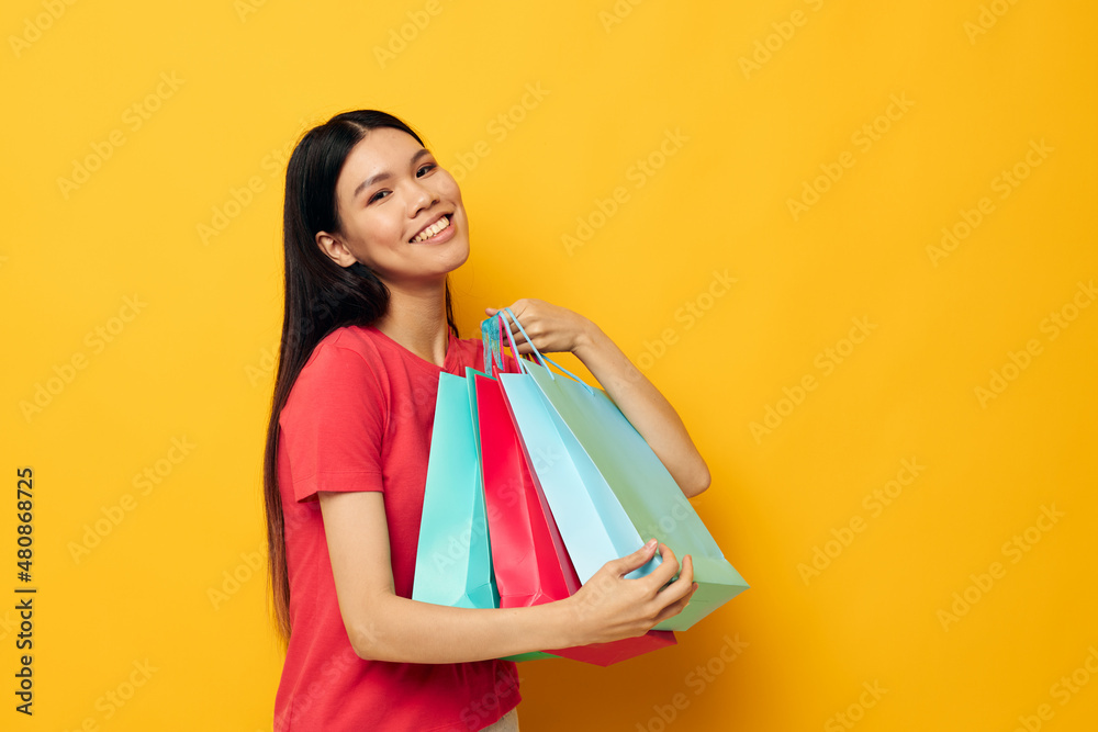 Portrait Asian beautiful young woman shopping bags in red t-shirt isolated background unaltered Portrait Asian beautiful young woman shopping bags in red t-shirt isolated background unaltered