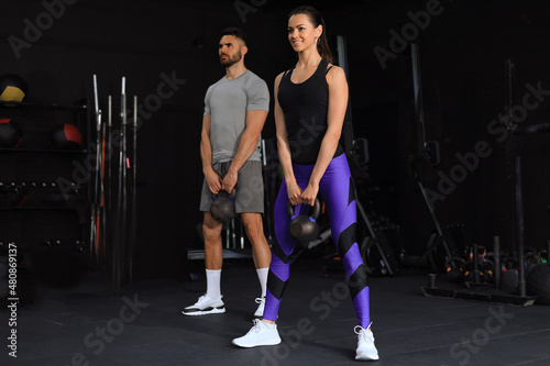 Fit and muscular couple focused on lifting a dumbbell during an exercise class in a gym.
