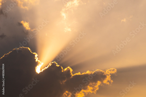 Abstract background of sun shines through the golden clouds in the evening.