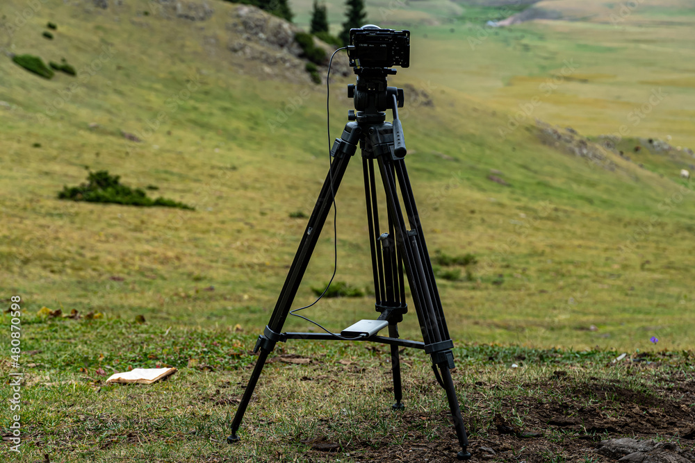 tripod with a video camera on the background of nature and mountains