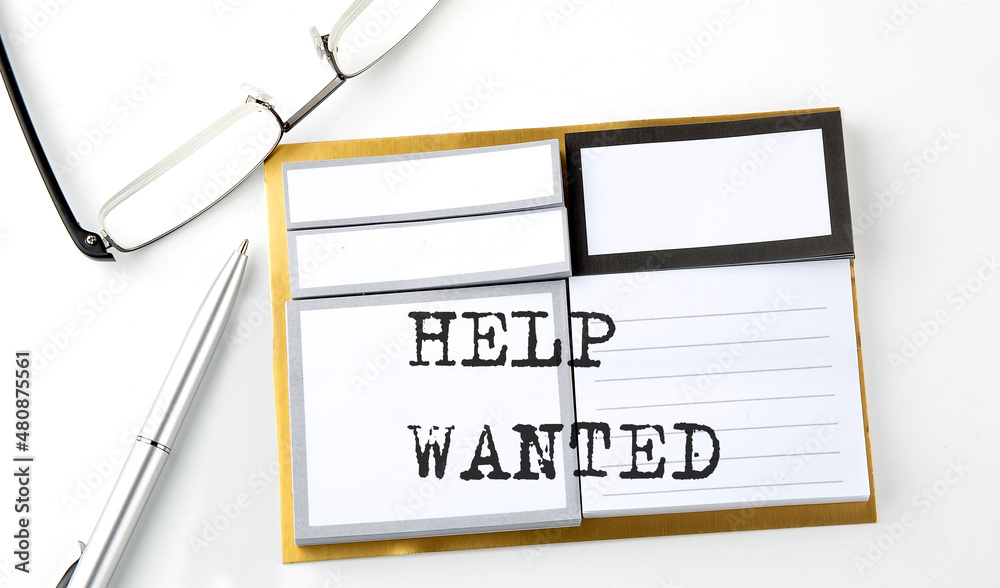 HELP WANTED text on the sticky notes with glasses and pen, business concept HELP WANTED text on the sticky notes with glasses and pen, business concept