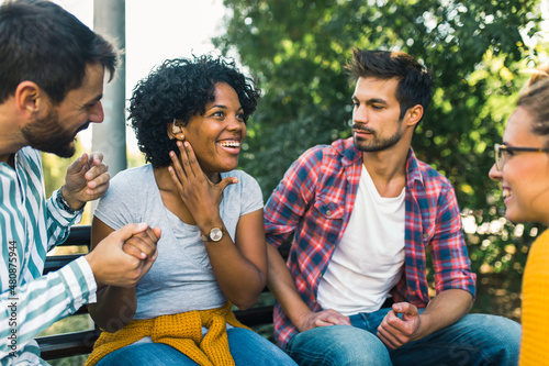 Woman with ear hearing problem having fun with her friends in the park photo