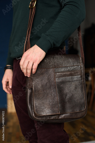 close-up photo of brown messanger leather bag on mans shoulder