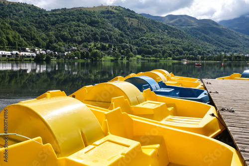 Group of colorful pedal boats next to the wooden pier of Lake Genos ,Loudenvielle, France. vacations, weekend getaways to unwind in nature. photo