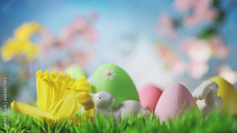Easter Bunny with Easter Eggs, Spring Flowers, Green Grass on Blue Sky background.