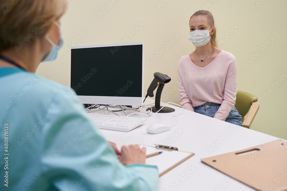 Young woman sitting in front of medical worker Young woman sitting in front of medical worker