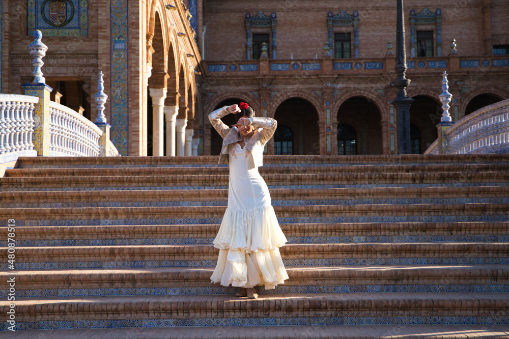 Flamenco dancer, woman, brunette and beautiful typical spanish dancer is dancing and clapping her hands on the stairs of a square in seville. Flamenco concept of cultural heritage of humanity.