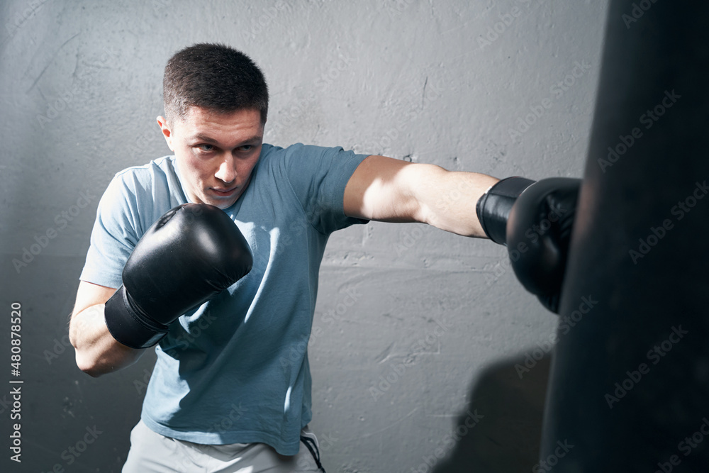 Focused young Caucasian male boxer training indoors Focused young Caucasian male boxer training indoors