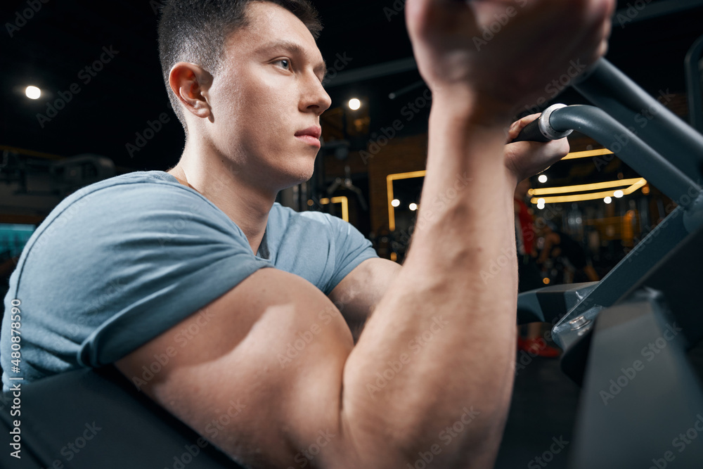 Professional bodybuilder is exercising on gym equipment