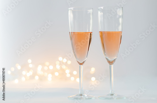 Glasses of sparkling Rose wine on white background with bokeh light for anniversary and Valentine's day concept.