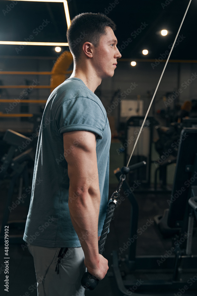 Concentrated athlete performing strength exercise on cable machine