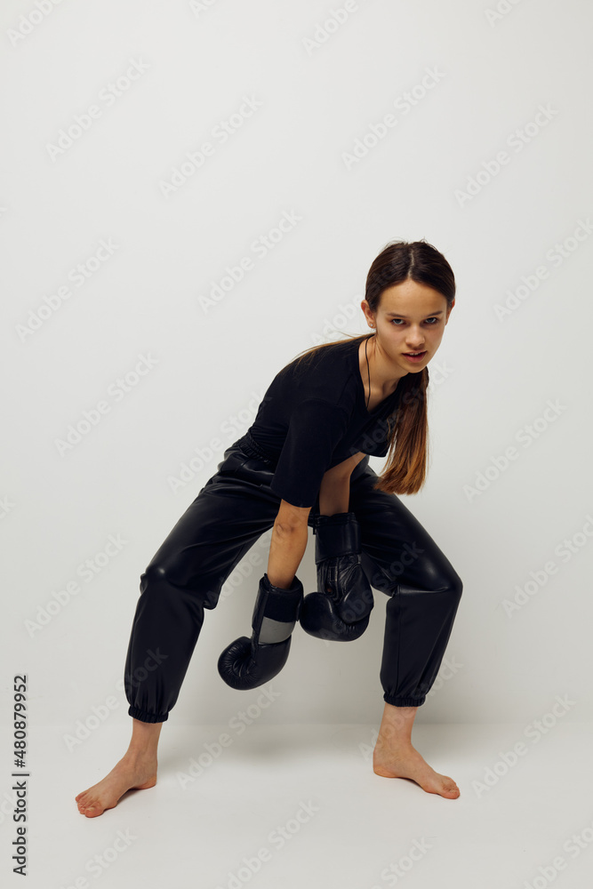 athletic woman in boxing gloves on the floor in black t-shirt light background
