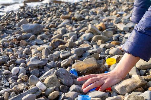 A child helps collect plastic garbage. Coastal cleanup day. Ecology and care for nature