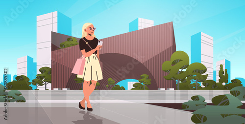 beautiful girl walking city street and using smartphone social media communication digital addiction concept
