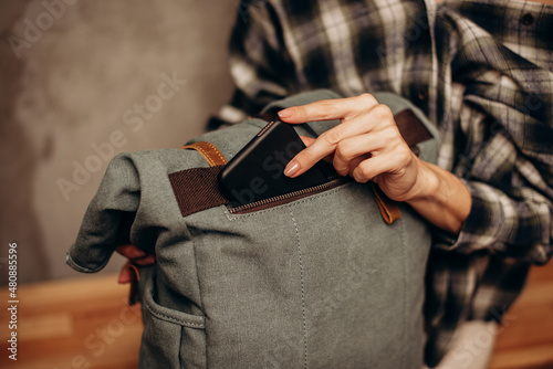 Young woman put smart phone into canvas bag