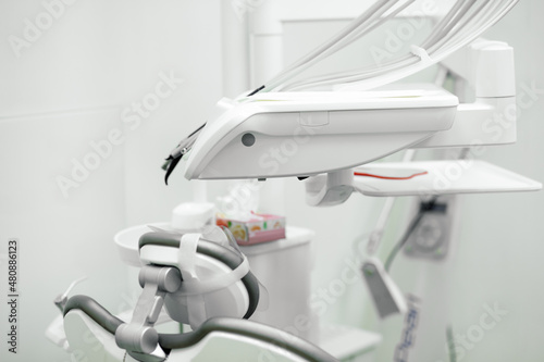 Empty modern dental chair with electric dentist tools included in main unit near cuspidor at dentist office. Interior.