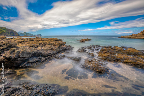 Long exposure, pacific ocean waves on rock in Playa Ocotal, El Coco Costa Rica. Famous snorkel beach. Picturesque paradise tropical landscape. Pura Vida concept, travel to exotic tropical country.