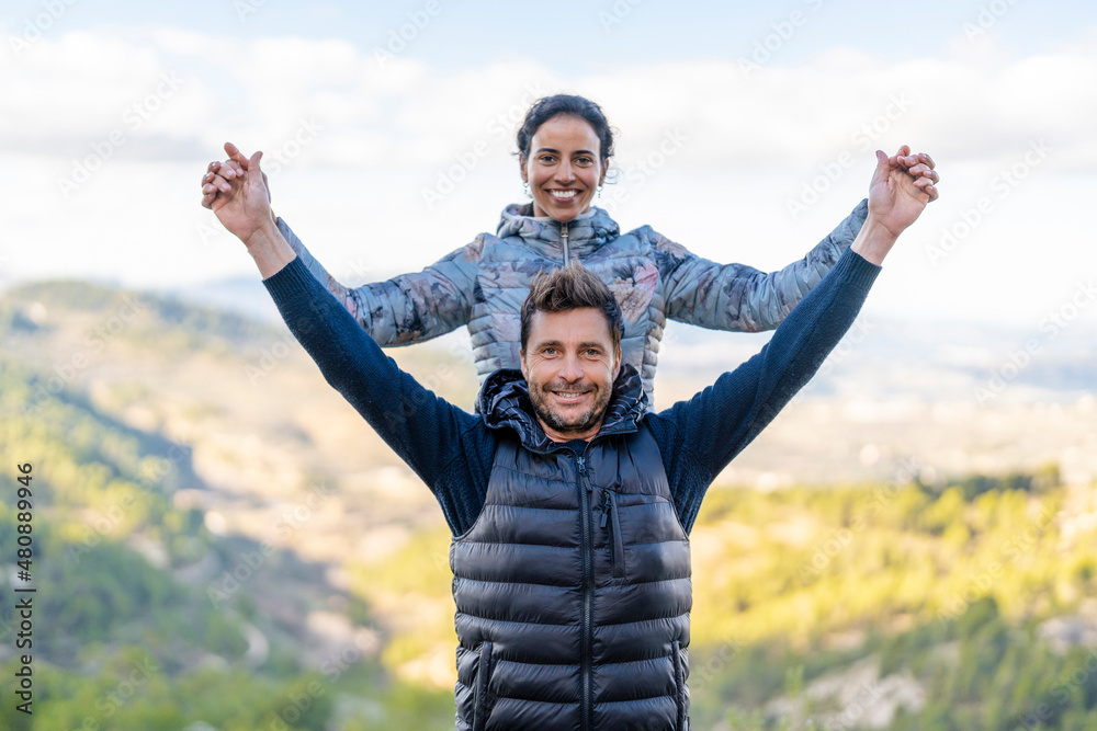 Smiling couple standing with arms outstretched at park Smiling couple standing with arms outstretched at park