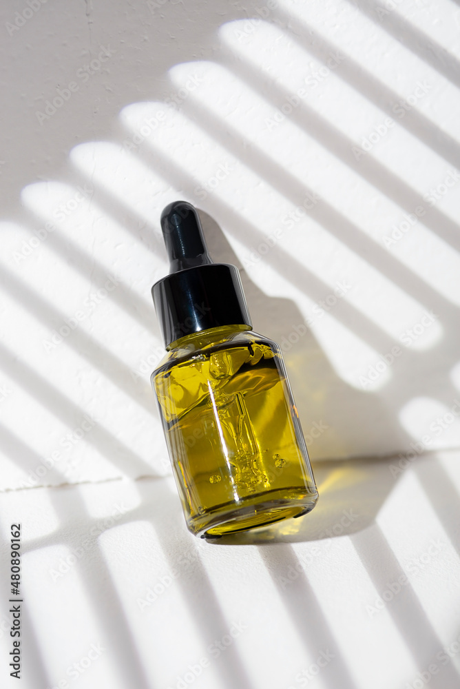 Green glass bottles with dropper pipette with serum or essential oil on a white background. Skincare cosmetic with beautiful shadows. Beauty concept for face body care. Green glass bottles with dropper pipette with serum or essential oil on a white background. Skincare cosmetic with beautiful shadows. Beauty concept for face body care.