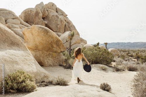 Woman in boho style leaping over a rock in the Joshua Tree desert 